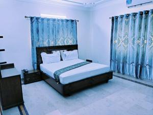 卡拉奇Karachi Family Guest House的一间卧室配有一张带蓝色窗帘的大床