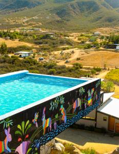 瓜达鲁佩镇Origen75 Loft - Villas - Skypool - Viñedo, Valle de Guadalupe的一座建筑的一侧,设有一座带壁画的游泳池