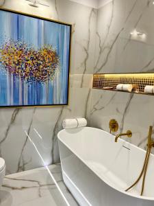 华沙MONDRIAN Luxury Suites & Apartments Old Town的带浴缸的浴室和墙上的绘画