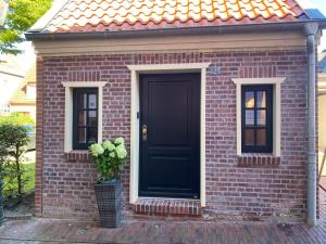 埃姆登Lüttje Huus Emden的砖房,有黑门和盆栽