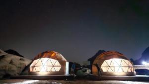 亚喀巴Bronze Mountains Camp Wadi Rum的两个圆顶在星空下点亮