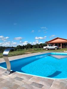 圣托梅-达斯莱特拉斯Pousada Colina das Maritacas的蓝色的游泳池,后面有一辆汽车