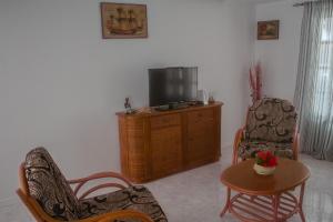 BeironaVila Paradise Sea & Swimming Pool View的客厅配有电视、2把椅子和1张桌子