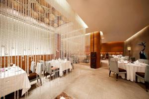 西安西安喜来登大酒店的一间设有白色桌椅和玻璃墙的用餐室