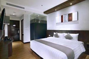 万隆Neo Dipatiukur Bandung by ASTON的卧室配有一张白色大床和镜子