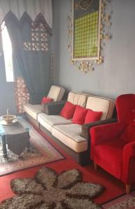 小笨珍Homestay ALHAQIM的带沙发和红色椅子的客厅