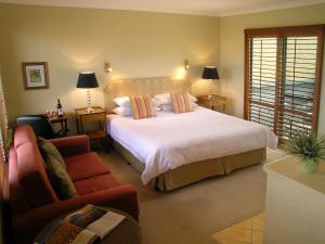 奥尔巴尼湾畔海滩酒店的卧室配有一张白色的大床和一张沙发。