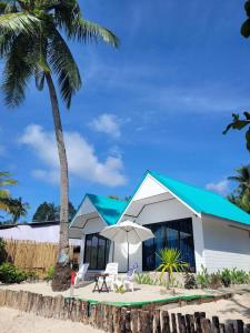班柯木Mook tawan Beach house的白色的建筑,有蓝色的屋顶和棕榈树