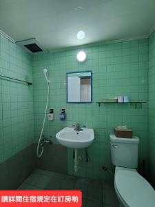 屏东县绿洲大旅社 的绿色瓷砖浴室设有卫生间和水槽