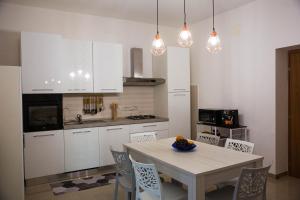 孔韦尔萨诺Doraci Home的厨房配有白色橱柜和桌椅
