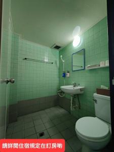 屏东县绿洲大旅社 的绿色瓷砖浴室设有卫生间和水槽