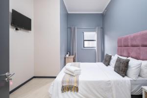 开普敦Cape palm royal guest house的卧室配有一张白色大床和粉红色床头板