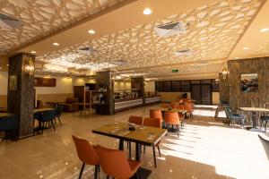 塔伊夫فندق زمان هوم لاند Zaman Homeland Hotel的一间带桌椅的餐厅和一间酒吧
