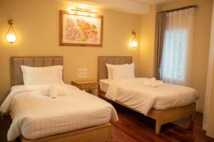 曼谷Siri Ratchadamnoen Bangkok Hotel的一间卧室设有两张带白色床单的床和窗户。