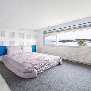 西归浦市济州转折点度假屋的一间卧室设有一张大床和大窗户
