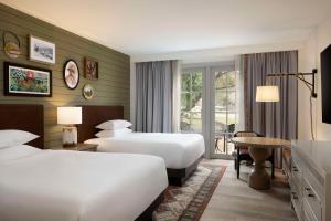 圣安东尼奥凯悦山乡村度假酒店及Spa中心的酒店客房设有两张床和一张桌子。