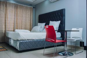 卢萨卡Stay Simple Lodge的一间卧室配有一张带红色椅子的床和一张桌子