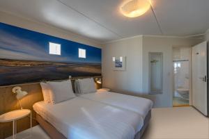 德科赫北海斯特兰酒店的一间带白色大床的卧室和一间浴室