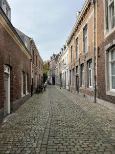 马斯特里赫特Monumentale stadswoning in hartje binnenstad的城市中一条空的鹅卵石街道,有建筑