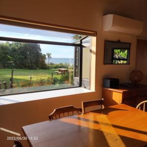 Parapara Beachfront Bliss - Your Parapara Seaside Retreat的用餐室设有享有庭院景致的大窗户。