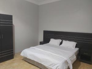 Al Qunfudhahاجنحة ارمادا的一间卧室配有一张大床和黑色床头板