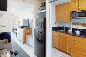 檀香山Island Colony 4218的厨房配有木制橱柜和黑色冰箱。