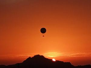瓦迪穆萨Petra Rose Apartment的日落时分飞过山的热气球