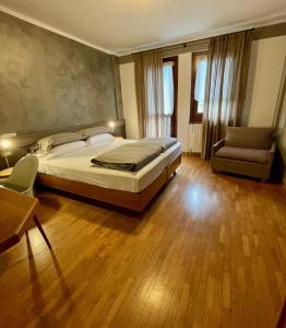 蓬泰迪莱尼奥Hotel Garni Sorriso的一间卧室配有一张床、一张沙发和一把椅子