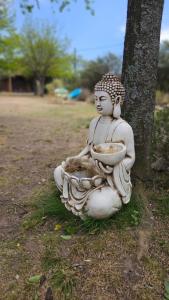 吉亚迪诺镇Sueño Zen的坐在树旁的草上的一个雕像