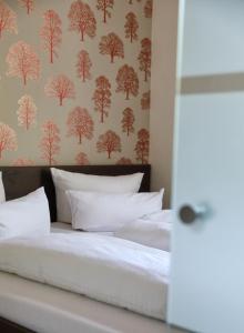 巴特利本施泰因凯瑟霍夫文化酒店的一张铺有白色床单的床和树木覆盖的壁纸