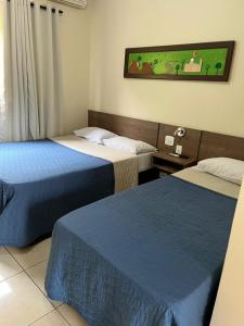 阿帕雷西达Hotel Vila dos Pescadores的一间酒店客房,设有两张床和电视