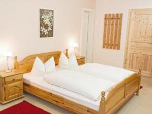 诺伊舍瑙贝佳斯霍夫鲁森酒店的一间卧室配有一张带白色床单的木床