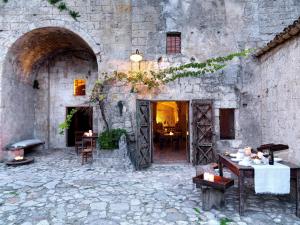 马泰拉勒格罗泰德拉奇维塔酒店的一座古老的石头建筑,配有桌椅