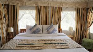 达兰萨拉Beaumont Glamping Eco Resort的一间卧室配有一张大床、枕头和窗帘