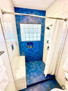 阿瓦隆The Edgewater的浴室设有蓝色瓷砖淋浴和窗户。