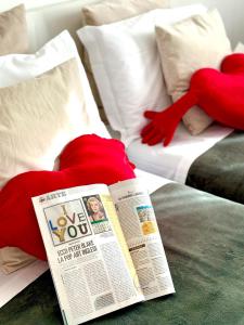 罗马Gemelli-San Pietro-Trastevere-casa con posto auto的报纸和床上的2个红色枕头