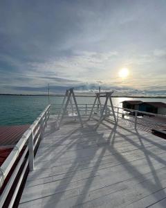 仙本那Egang-egang Resort Bum-Bum Island Semporna的水面上的一个木制码头,阳光照耀着