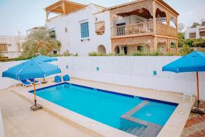 Qaryat at Ta‘mīr as Siyāḩīyah4 bedrooms villa with private pool in Tunis village faiuym的房屋前的带蓝色遮阳伞的游泳池