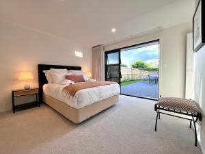 汉密尔顿Luxury Villa, Central, Golf and Cafés - By KOSH BNB的一间卧室设有一张床和一个大型滑动玻璃门