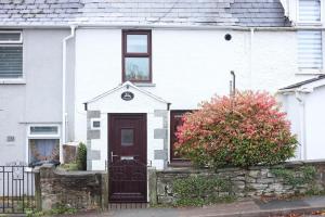 May Cottage, Sofa Bed, Garden的一间白色的房子,有棕色的门和灌木