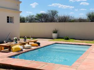 哈博罗内Mmaset Houses bed and breakfast的后院的游泳池,配有桌子和野餐桌