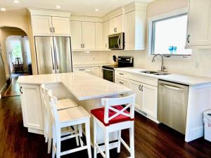 卡尔加里Crescent Heights Majesty的厨房配有白色橱柜和带红色座椅的柜台。