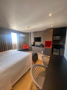 巴西利亚Lindo Flat Part Grand Mercure Varanda aconchegante的酒店客房带一张床、一张桌子和椅子