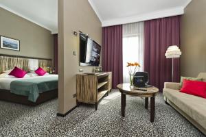 西维德尼察Hotel Fado Spa & Restaurant的酒店客房配有床、沙发和电视。