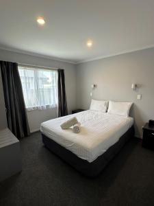 奥波蒂基Eastland Pacific Motor Lodge的卧室配有一张带白色床单的大床和窗户。