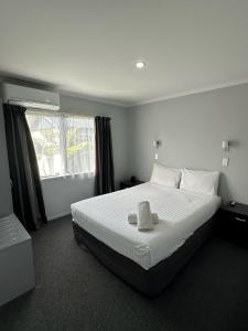 奥波蒂基Eastland Pacific Motor Lodge的卧室配有白色的床和毛巾