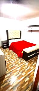 瓦拉斯Departamento Amoblado的一间卧室设有红色的床,铺有木地板。