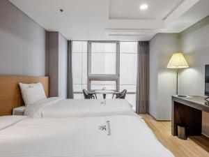 釜山Haeundae Seacloud Hotel Residence的酒店客房设有两张床和一张桌子。