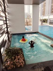 新山Sky Tree Studio Apartment at Bukit Indah, Johor的两人在带冲浪板的游泳池