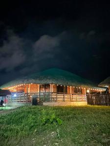马斯巴特Maria Kulafu Kubo House 1 BIG BEDROOM with Wifi的一间在晚上有草屋顶的大小屋